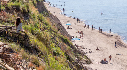 Karkle. Olado Kepure. Baltic sea coast. Forest by the sea. High Cliff. People are resting on the shore. A narrow beach at the foot of the cliff. People walk and sunbathe on the coast. Pine forest 