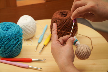 Crocheting Amigurumi technique, close up photo of hands making doll using crochet stitches