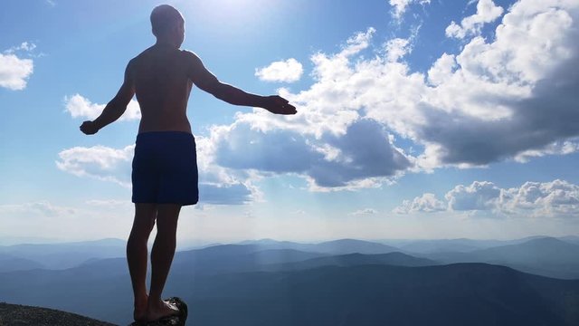 man stands on top of a mountain with open hands. at the top of the mountain, a man with his arms spread wide.