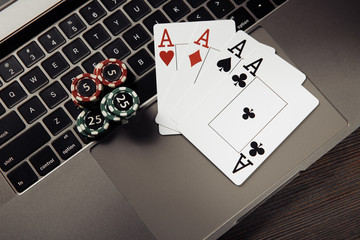 Stack of gambling chips and playing cards on keaboard. Online casino concept. Top view
