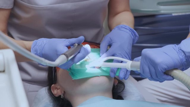 Close Up Of A Young Woman's Hand A Dentist And Assistant Prepare For Surgery Make An Examination Put A Protective Elastic Band On The Patient's Teeth In The Hospital Office