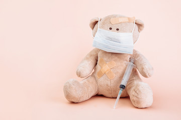 Stuffed Bear animal in mask with syringe isolated on pink background. Pediatrician concept.