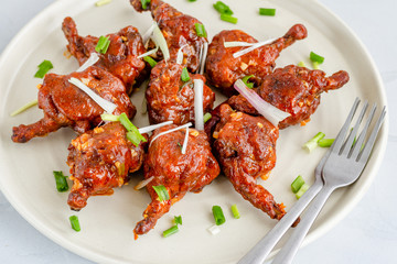 Chicken Lollipop - Popular Indo-Chinese Chicken Appetizer on a White Plate Garnished with Scallion Close Up Horizontal Photo
