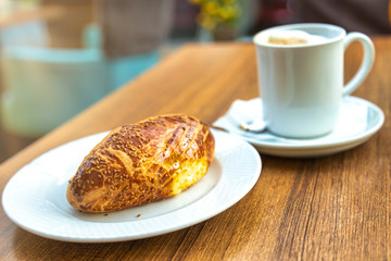Sezam bun with coffee on the cafe table. Still life closeup of the fresh bun with cheese and olives. Arab coffee style.