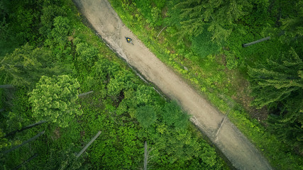 Aerial shot of mountainbike woman riding on bike in summer mountains landscape. Woman cycling MTB outdoor adventure gravel single trail.