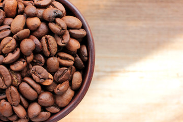Cup of coffee beans on a wooden table from above. Close-up of coffee beans in a brown ceramic cup on wood background with copy space. Rustic style. Flat lay