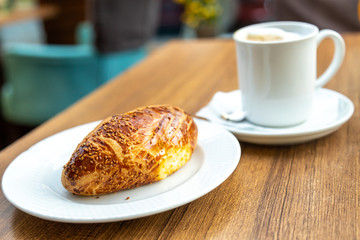 Sezam bun with coffee on the cafe tebale. Still life closeup of the fresh bun with cheese and olives. Arab coffee style.