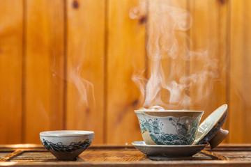 Cup of chinese tea with cloud of steam on wooden background