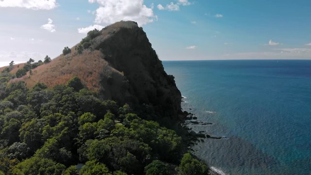 Drone footage flying over the southern tip of St. Lucia approaching a mountainous Piton hugging the coast.