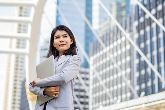 Business woman hold a laptop while standing on the property business background.