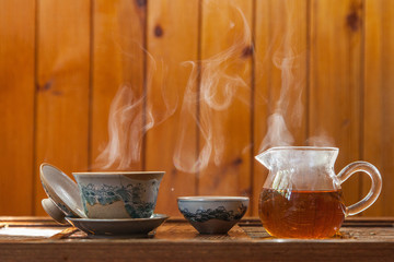 Chinese tea cup and glass kettle  with cloud of vapor on wooden background