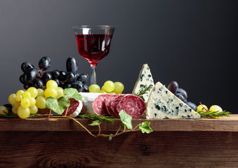 Red wine and snacks on an old wooden table.
