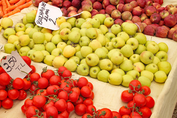 Tomatoes and apples on display on a market stall