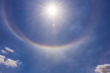 Fantastic beautiful sun halo phenomenon or sun with circular rainbow and fluffy altocumulus clouds...