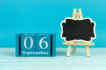 wooden calendar with the date of August 6 and an easel on a blue background, place for text	