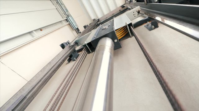 Elevator lift cabin moves up inside illuminated elevator shaft with hydraulics with many floors slow motion