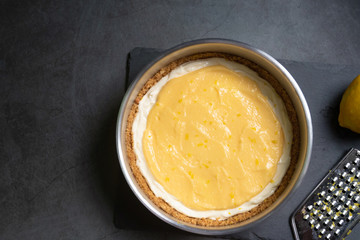 Delicious homemade honey lemon cheese pie and juicy lemon curd in a mold on black table background.