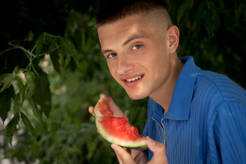 young smiling guy eats a slice of watermelon