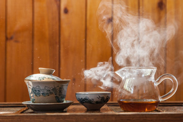 Chinese tea cup and glass kettle  with cloud of vapor on wooden background