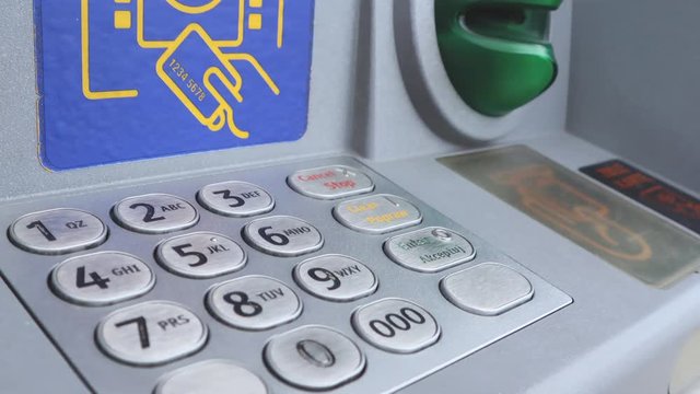 The girl drives the PIN code at the ATM.