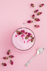 Top view of rose moon milk in glass cup on the pink surface. Location vertical.