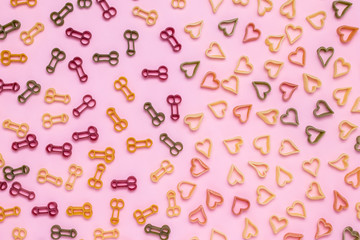 Abstract pattern of pasta in the shape of heart and phallus icon on pink paper background. Symbol of love, sexual health. Romantic concept. The holiday is the day of lovers, valentine's day.