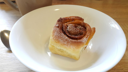 Delicious cinnamon roll on a white plate. Sweet pastries.