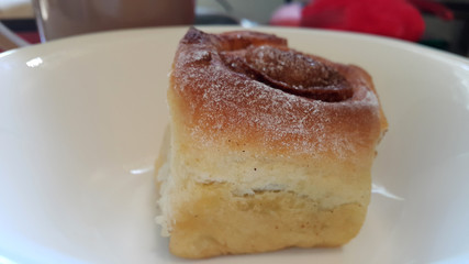 Delicious cinnamon roll on a white plate. Sweet pastries.