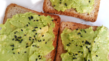 Baked toast with avocado on a white plate. Vegan food. Vertical photo