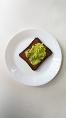 Baked toast with avocado on a white plate. Vegan food.	
