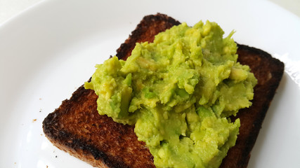 Baked toast with avocado on a white plate. Vegan food.