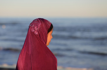 young girl with veil on head waiting by the sea