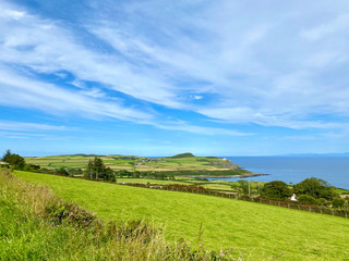 Fototapeta na wymiar Green fields and coast looking towards the village of Maughold, on the Isle of Man, British Isles