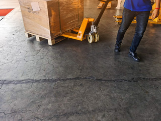 Worker driving forklift loading shipment carton boxes and goods on wooden pallet at loading dock from container truck to warehouse cargo storage in freight logistics and transportation industrial