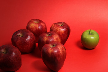 muchas manzanas rojas y una manzana verde sobre fondo rojo