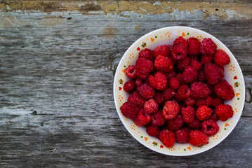 .fresh raspberries in a plate on a wooden background