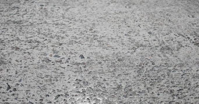 Hard concrete asphalt pavement road surface. Zoom closeup scene while camera smoothly and stabilized filming textured surface macro shot. 