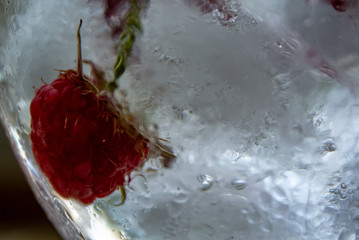 .water with raspberries and ice in a glass