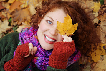 jeune et jolie femme rousse dans un parc arboré en automne avec des feuilles mortes