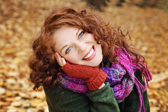 jeune et jolie femme rousse dans un parc arbor&eacute; en automne avec des feuilles mortes