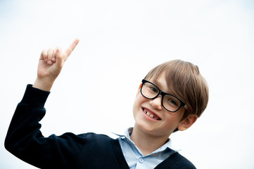 A schoolboy with glasses points up. Concept back to school