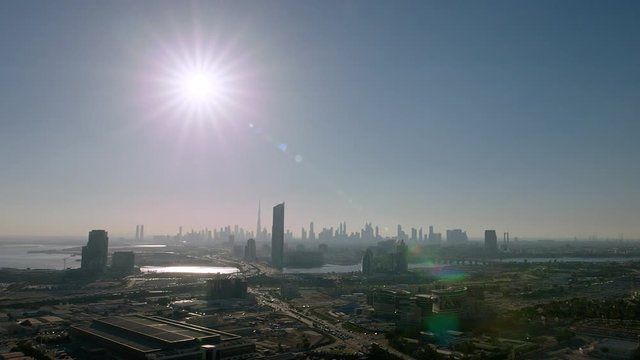 An aerial shot showing the development of Dubai Festival City area panning left then right pass Business Bay Crossover Bridge & the Dubai Skyline, Pan Right, 6-axis stabilized gimbal, Shotover F1, 8K.