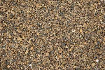 Small stones of seamless texture. Seamless surface texture covered with small dark brown stones.