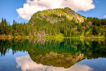 A clear alpine lake with a mountain in the background and reflections on the water