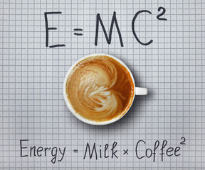 A cup of coffee with whipped cream is on a checkered paper sheet with funny formulas.