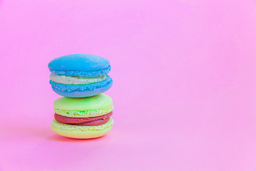 Sweet almond colorful unicorn blue yellow macaron or macaroon dessert cake isolated on trendy pink pastel background. French sweet cookie. Minimal food bakery concept Copy space