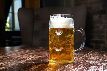 Fresh beer in a large mug on a wooden table