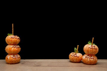 Halloween face on the peeled whole tangerine or mandarine orange fruits. Halloween minimal concept.