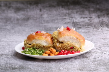 Dabeli is an Indian snack item served with Pomegranate Seeds and Cilantro in white ceramic plate. It's a popular Navratri Festival food