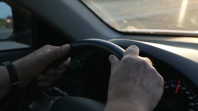 Close-up of a man's hand on the steering wheel while driving a car. Man driving a car